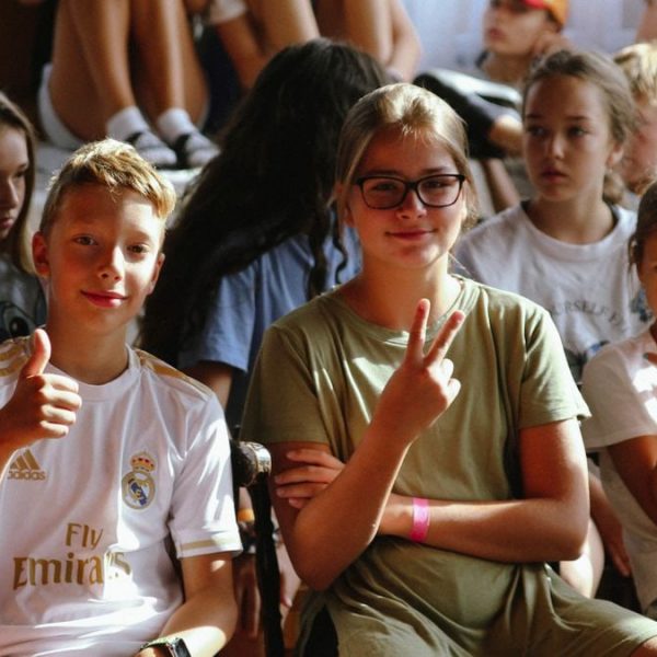 Cheerful group of children sitting together at an indoor event, showcasing friendships and diversity.